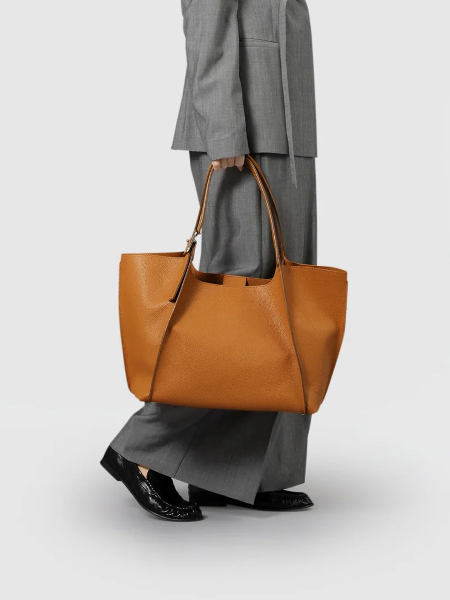 Person in gray suit carrying a large tan handbag.