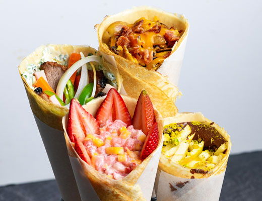 Four colorful crepes filled with various fruits and vegetables.