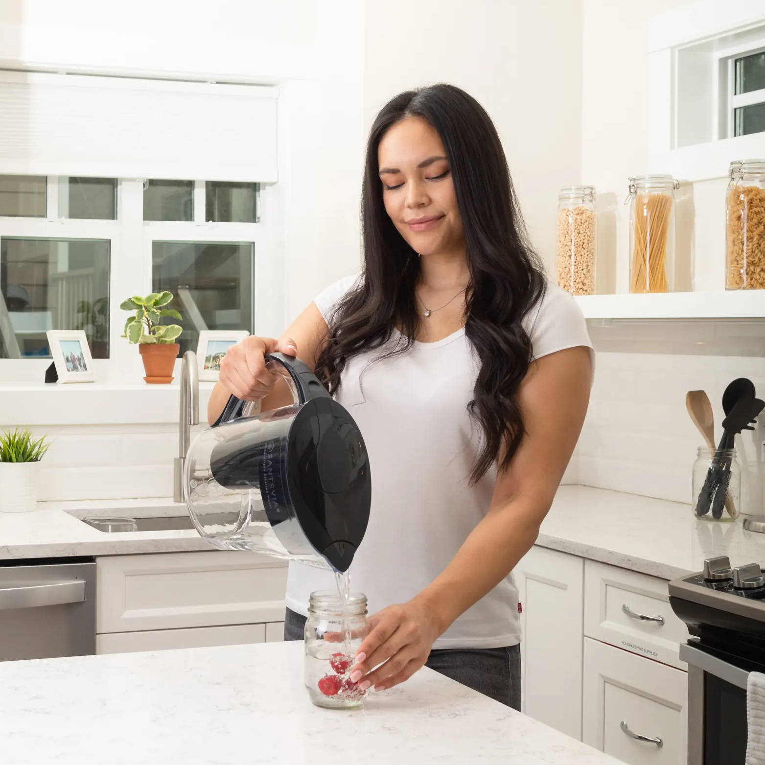 Woman pouring water into cup with strawberries