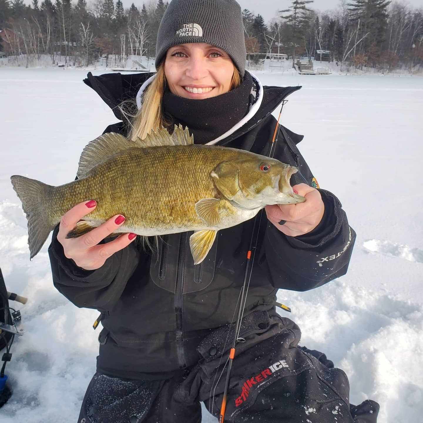 Amy Hansend holding a small mouth caught through the ice with a WST Whisker Stick