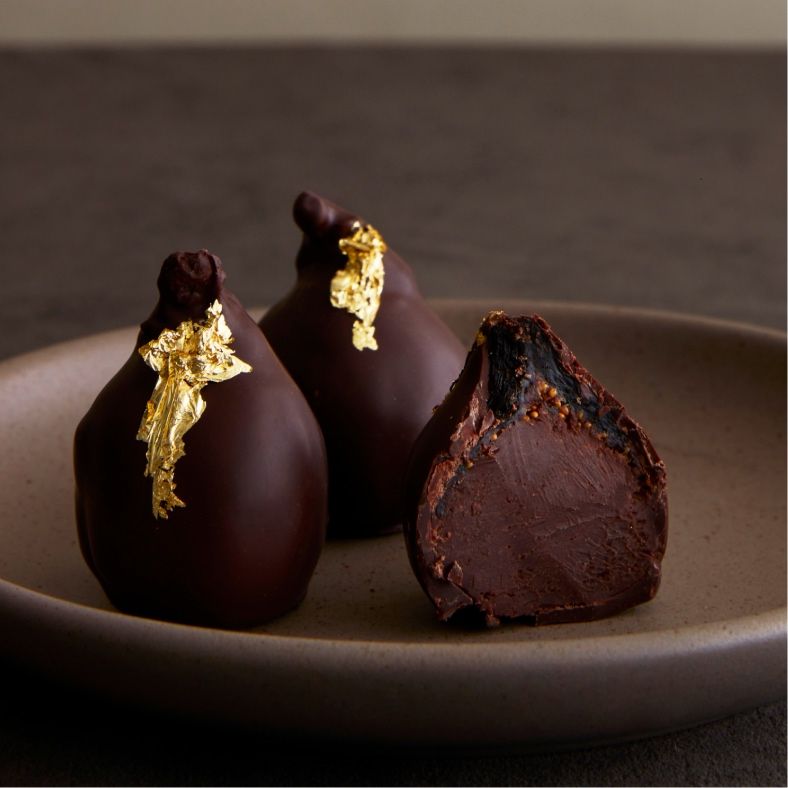 Chocolate truffles with gold leaf on a ceramic plate.