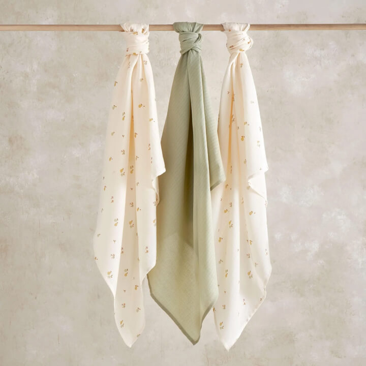 Three scarves hanging on a rod against a light background.