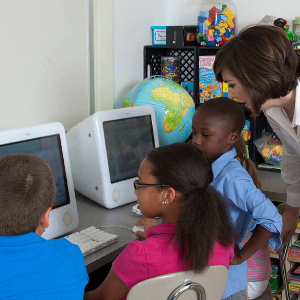 students with teacher in classroom using computers