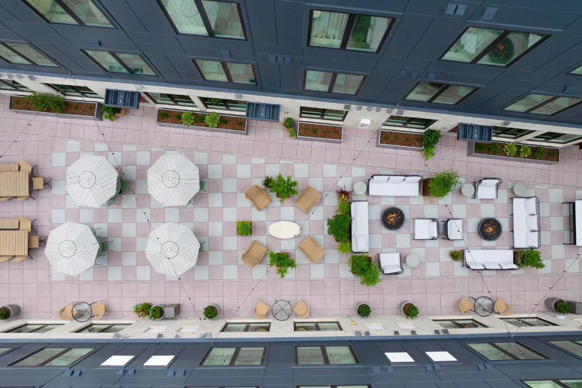 Aerial view of a hotel rooftop terrace showing outdoor furniture zones, dining areas, lounge seating, and clear circulation paths 