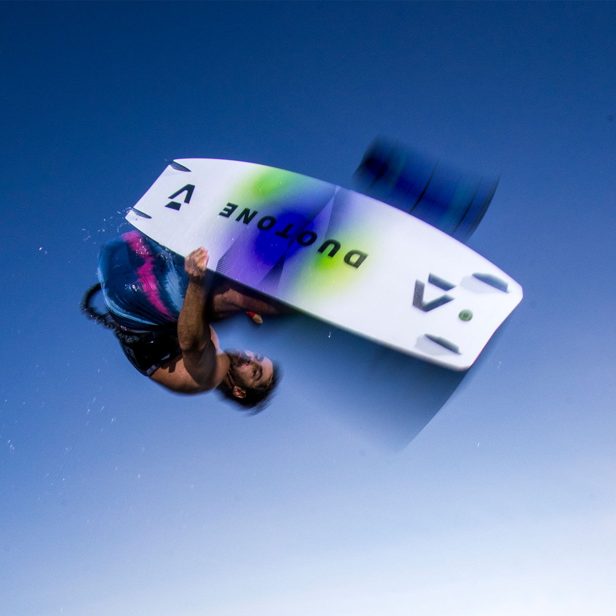 Person performing a trick on a wakeboard against a blue sky.