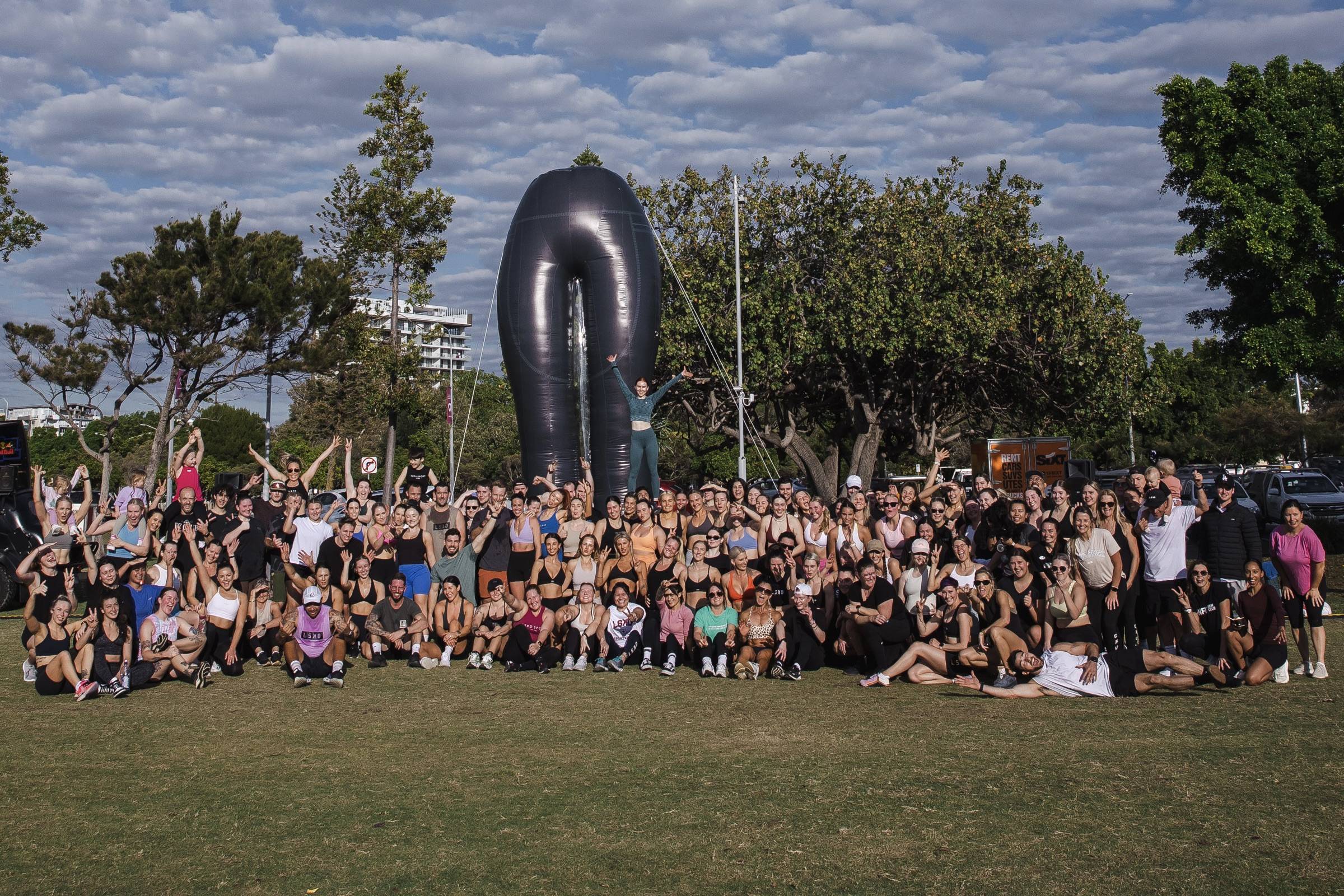 group of people working out in the park next to giant inflatable tights