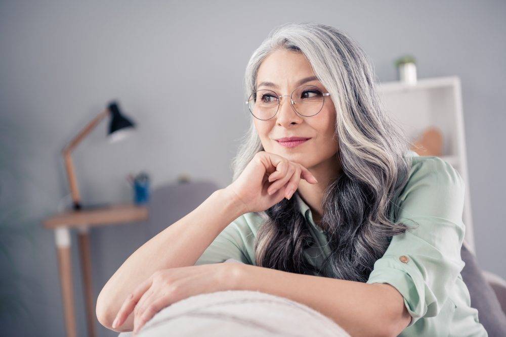 Woman with grey hair wearing round metal glasses
