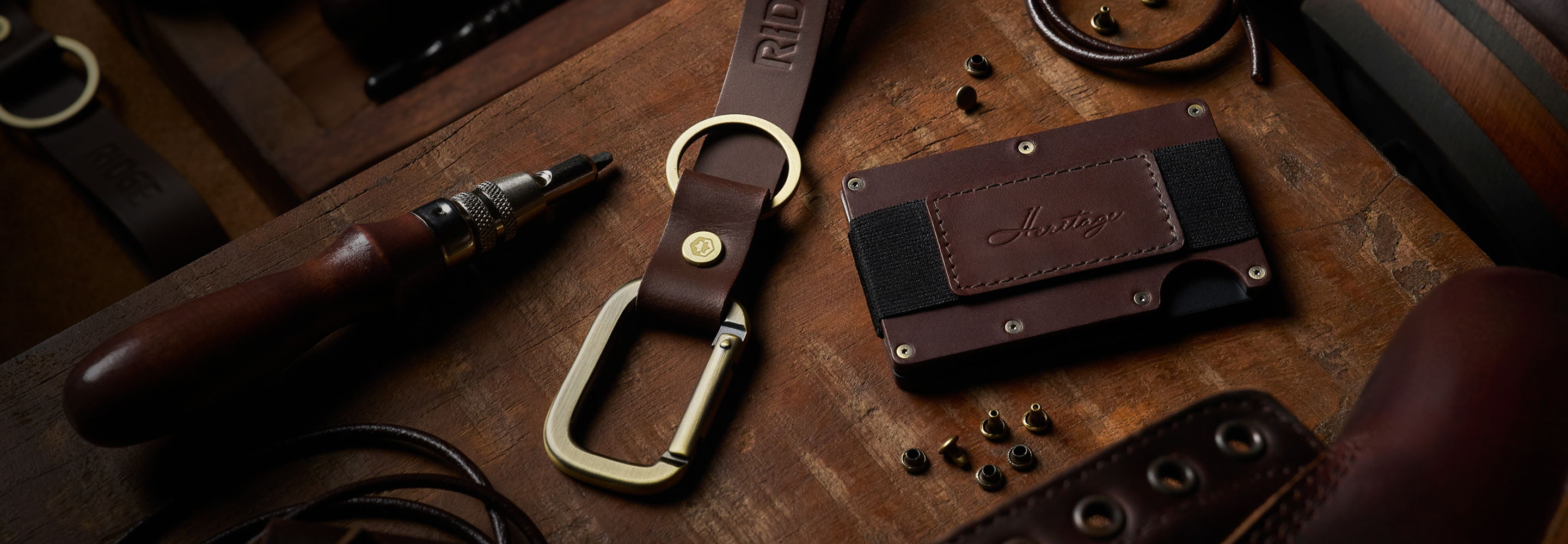 Leather goods and accessories arranged on a wooden surface.