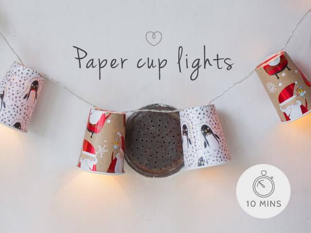 A hanging paper cup decorations glowing with warm white lights.
