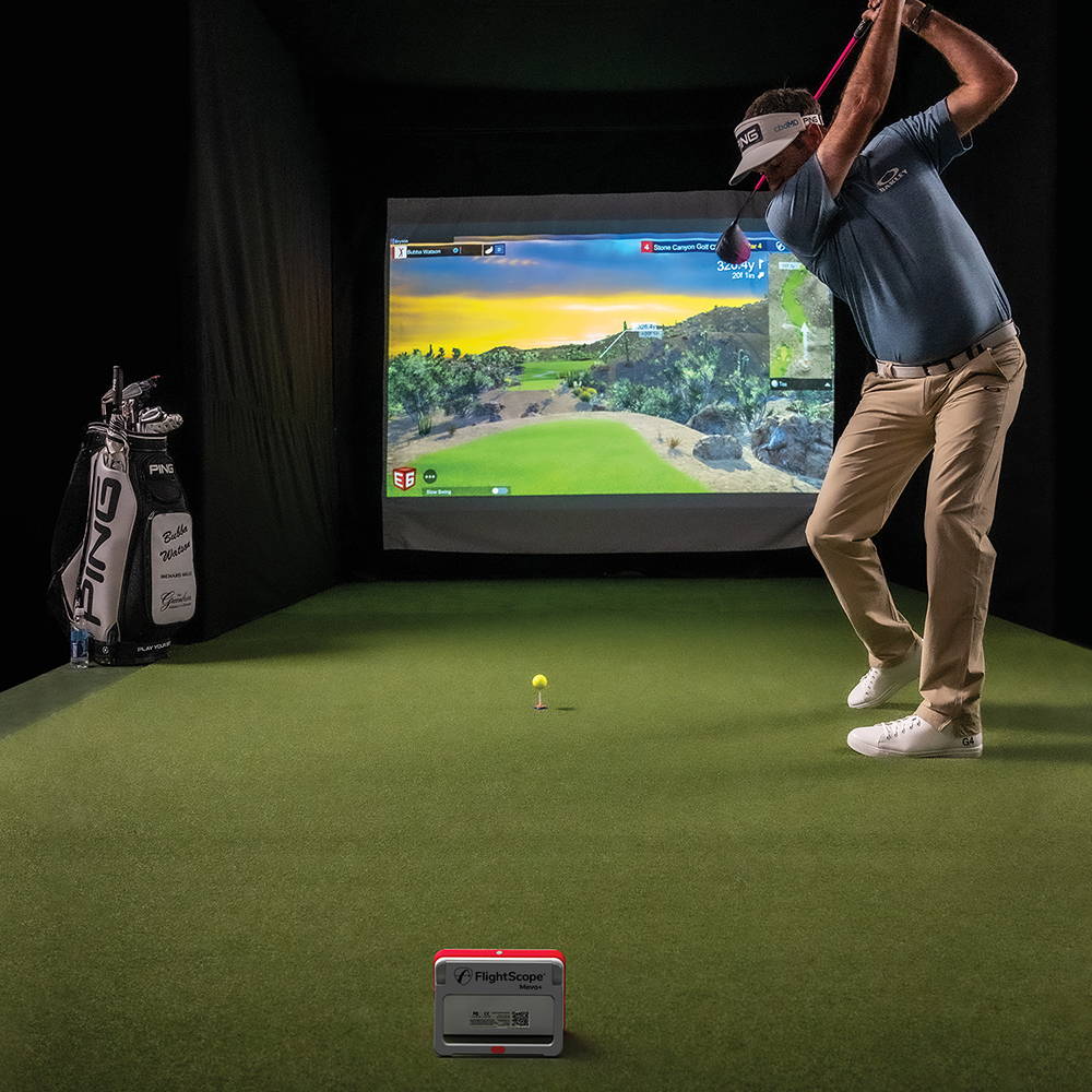 A golfer getting ready to swing in a golf simulator with the FlightScope Mevo Plus
