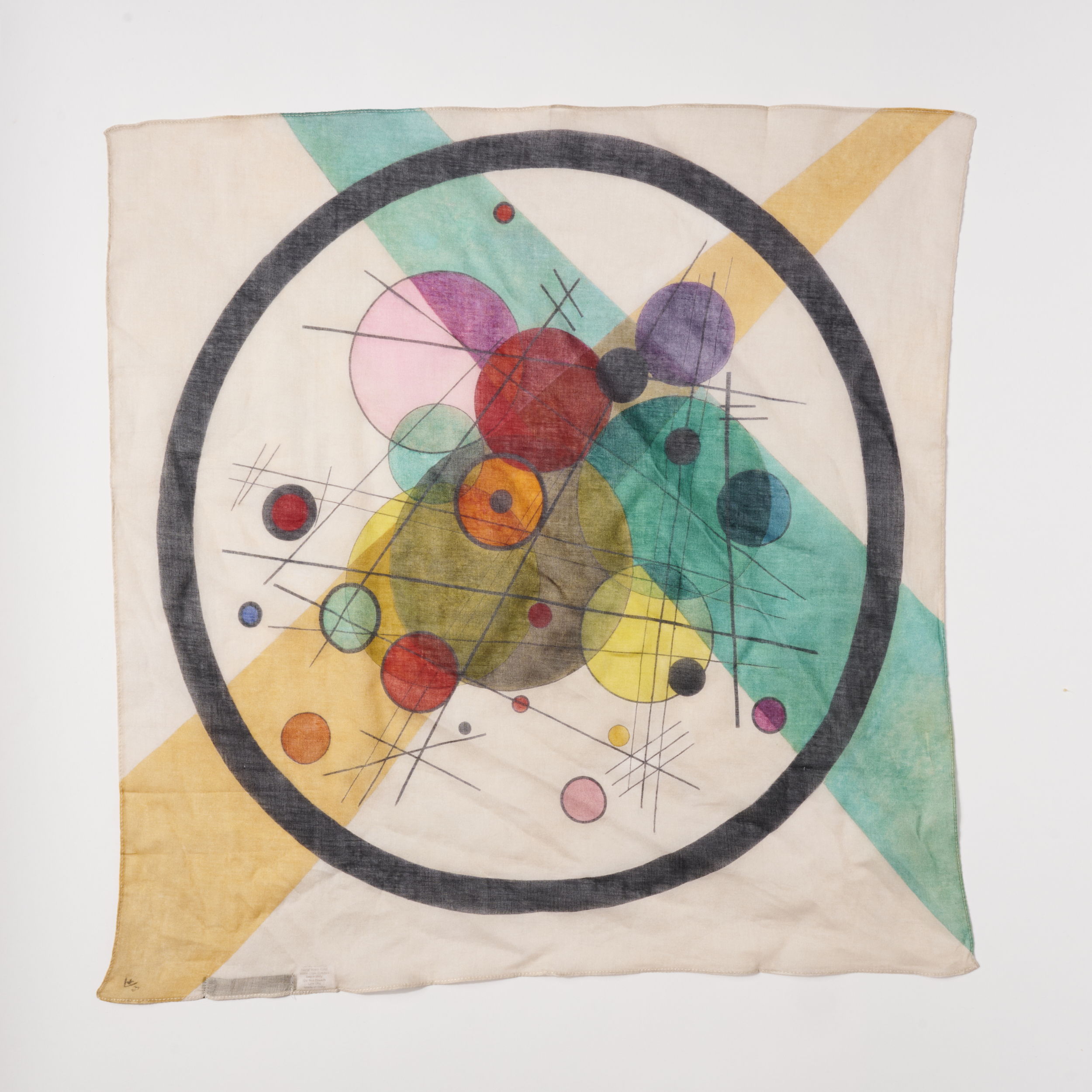 Scarf with abstract design featuring colorful circles and geometric shapes on a cream background.
