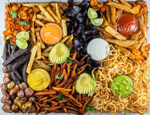 A colorful assortment of fries, dips, and vegetables on a platter.