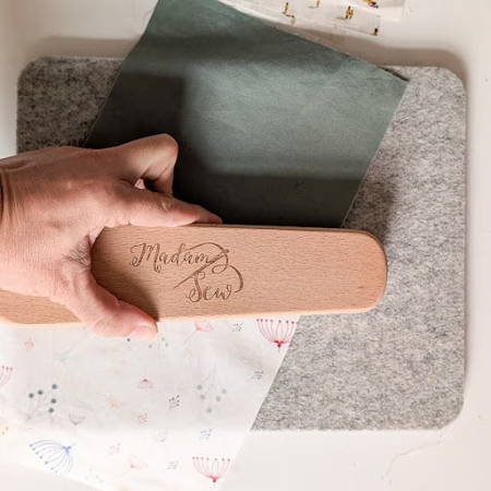 Hand holding a clapper to press a seam flat