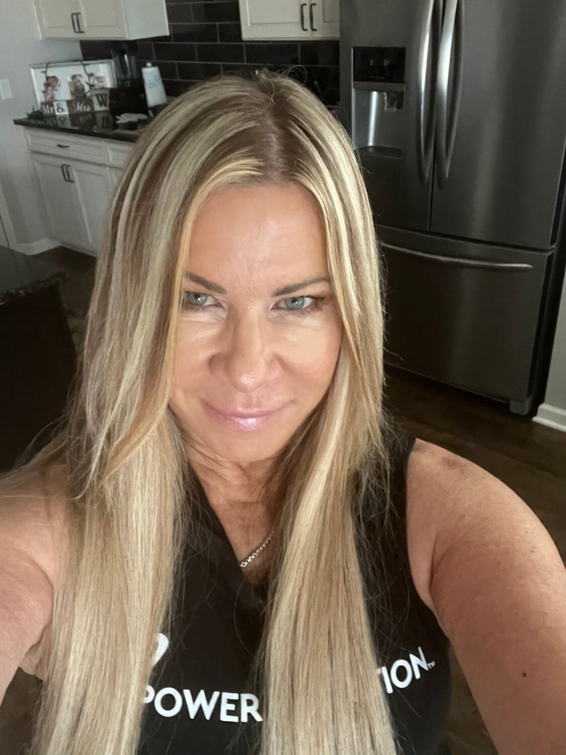 Smiling woman with long blonde hair in a kitchen setting.