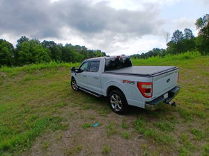 Rear three-quarter view of white Ford F-150 in field