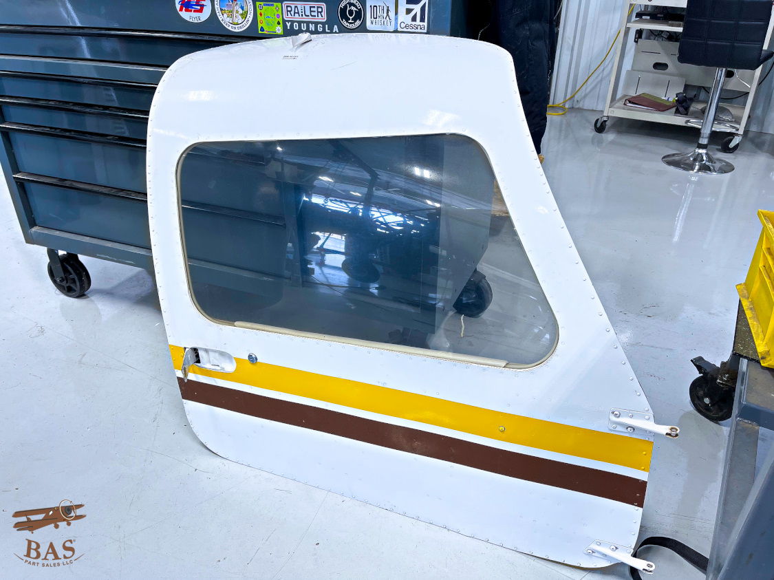 White aircraft door with a window, resting on a workshop floor.