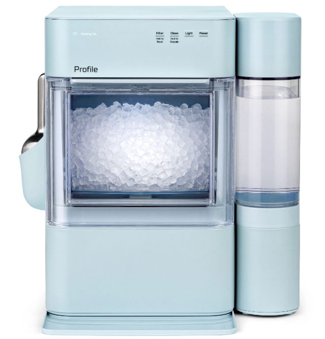 A light blue countertop ice maker with a transparent ice storage compartment.