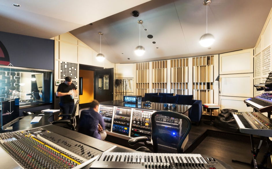 A modern music studio with equipment and two people working.