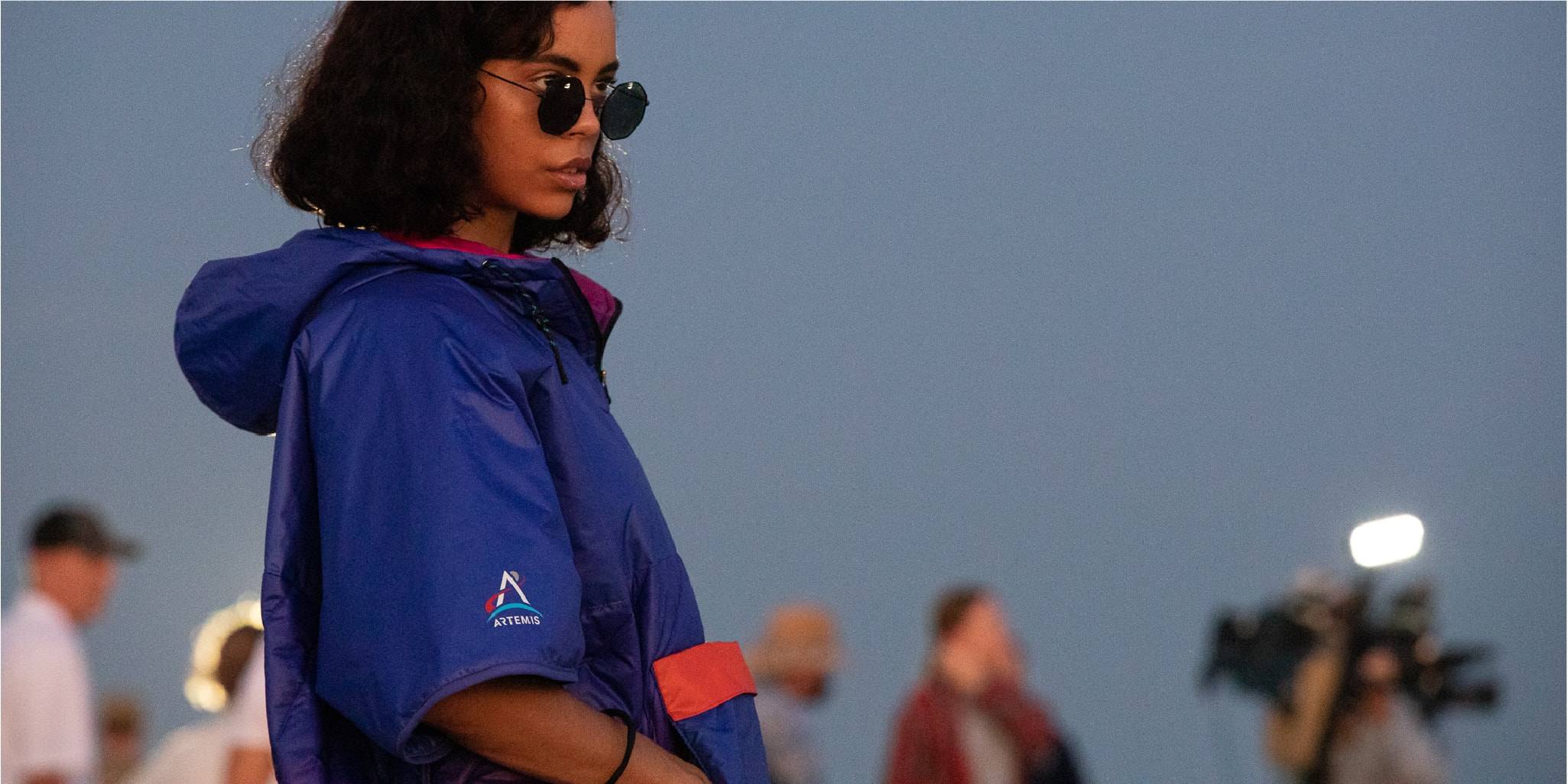 Woman watching rocket takeoff in NASA Artemis Poncho by Rumpl