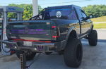 Rear three-quarter view of lifted Ram pickup with custom bumper and bed rack at Royal Farms gas station