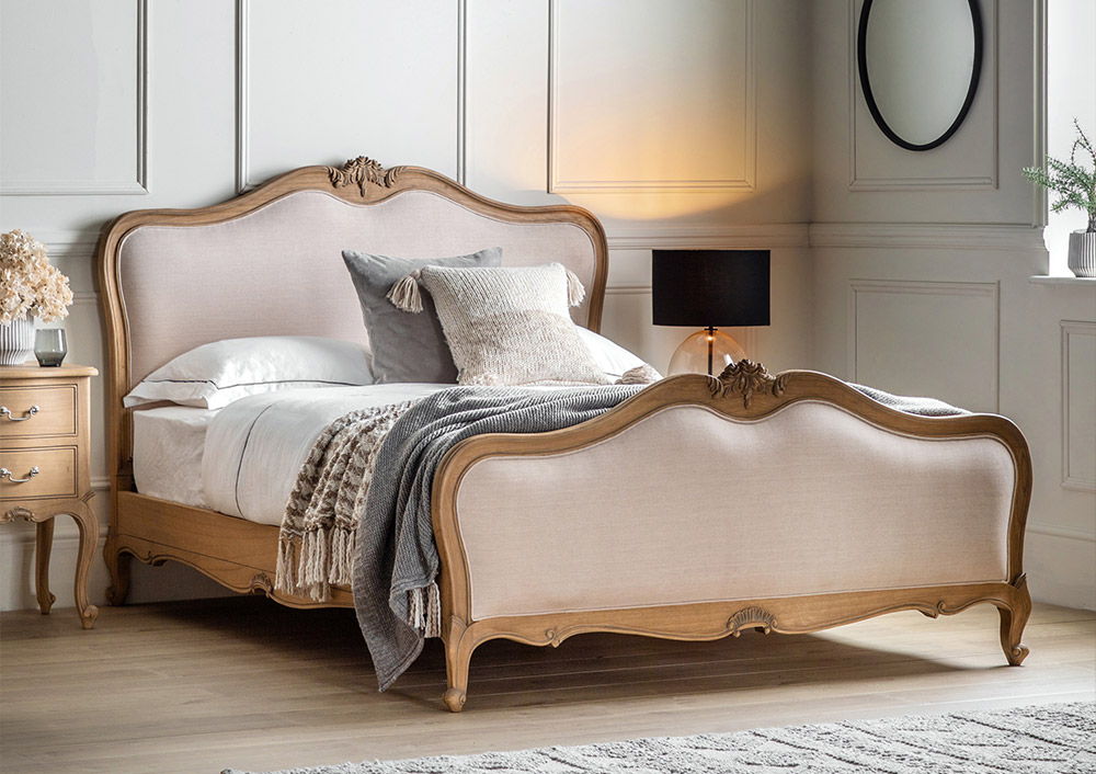 Elegant French style bedroom with a bed, pillows, and decorative throw.