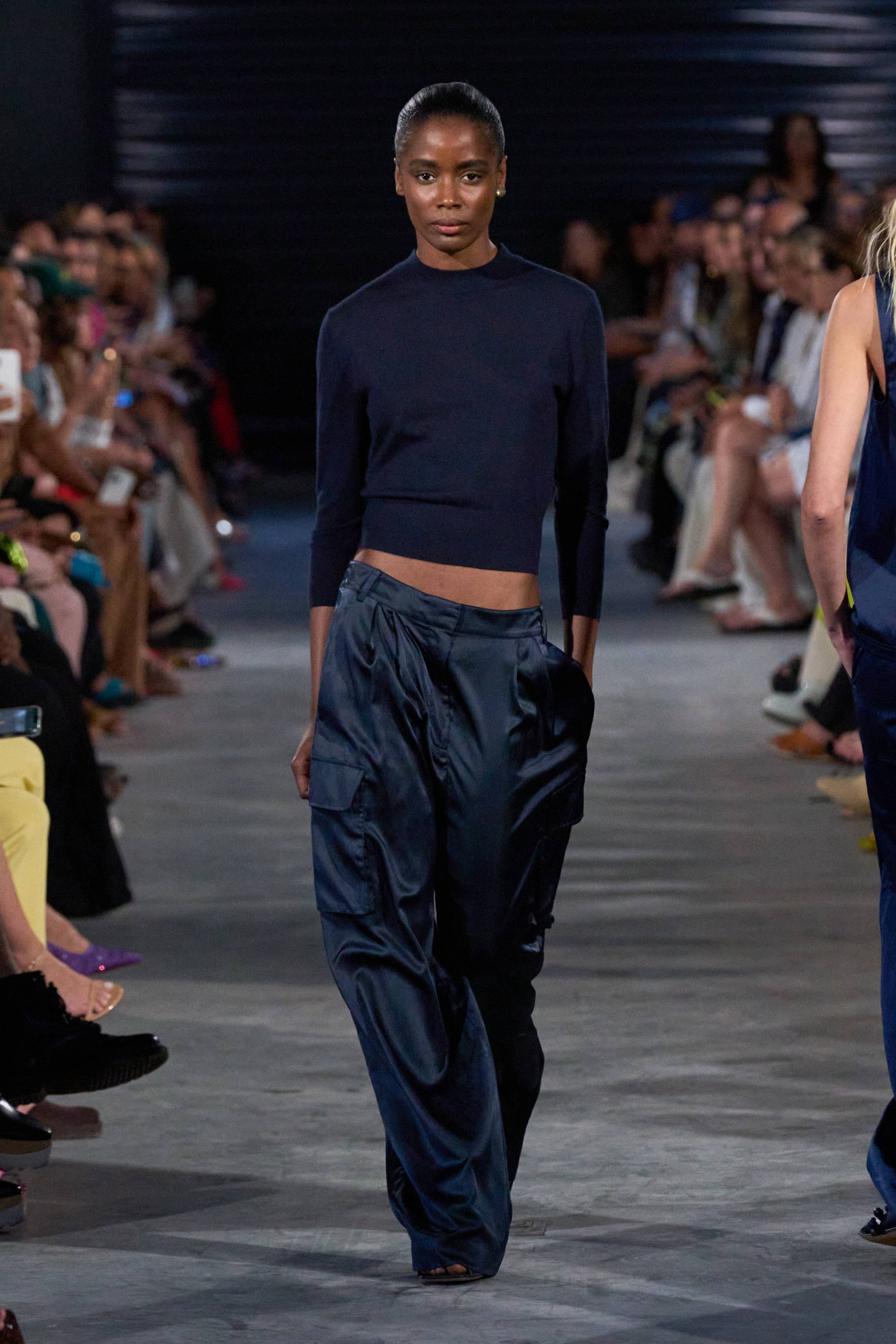 Model on a runway wearing sweater and pants