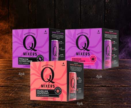 Three boxes of Q Mixers in different flavors on a wooden surface.