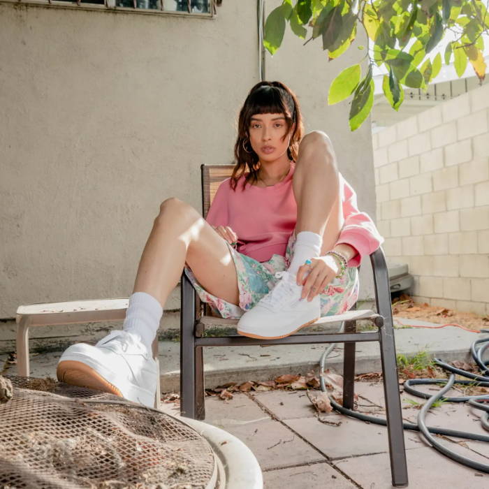 woman sitting on backyard chair wearing reebok sneakers