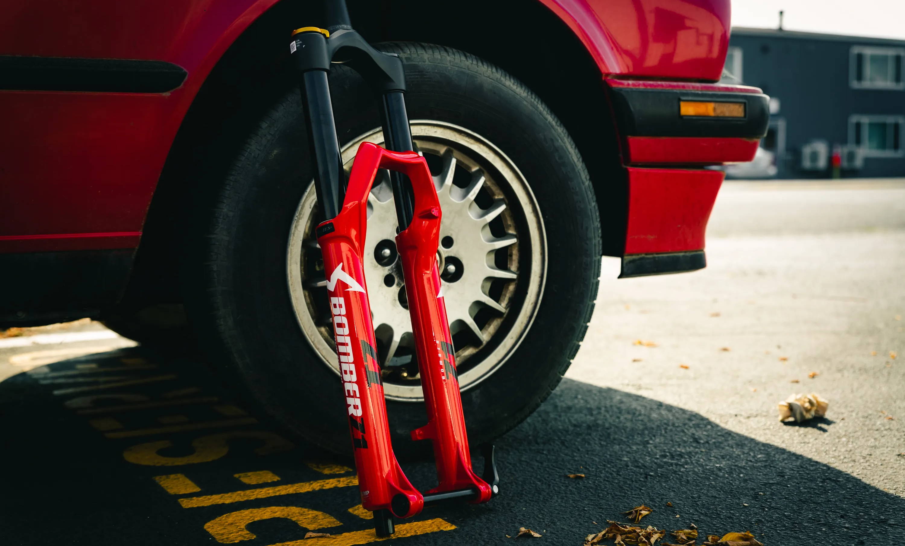red marzocchi bomber z1 mountain bike fork leaning against a red bmw e30