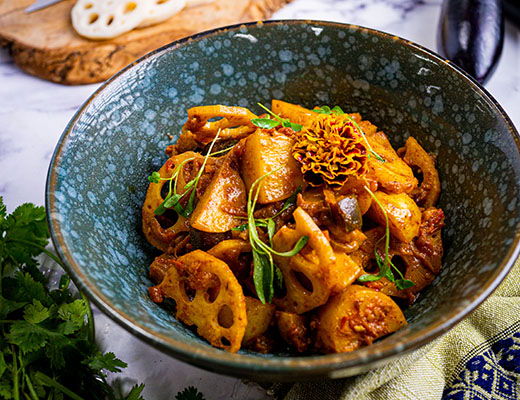 Bowl of stir-fried lotus root with spices and herbs.