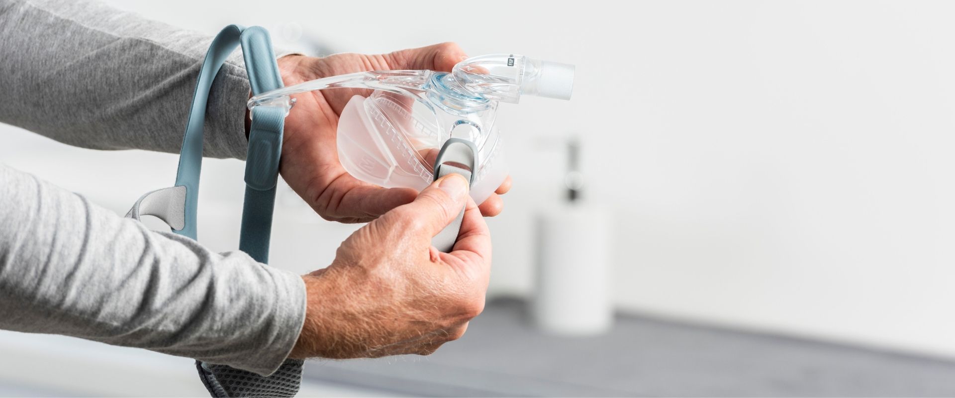 Person holding a medical device with a hose in a clinical setting.