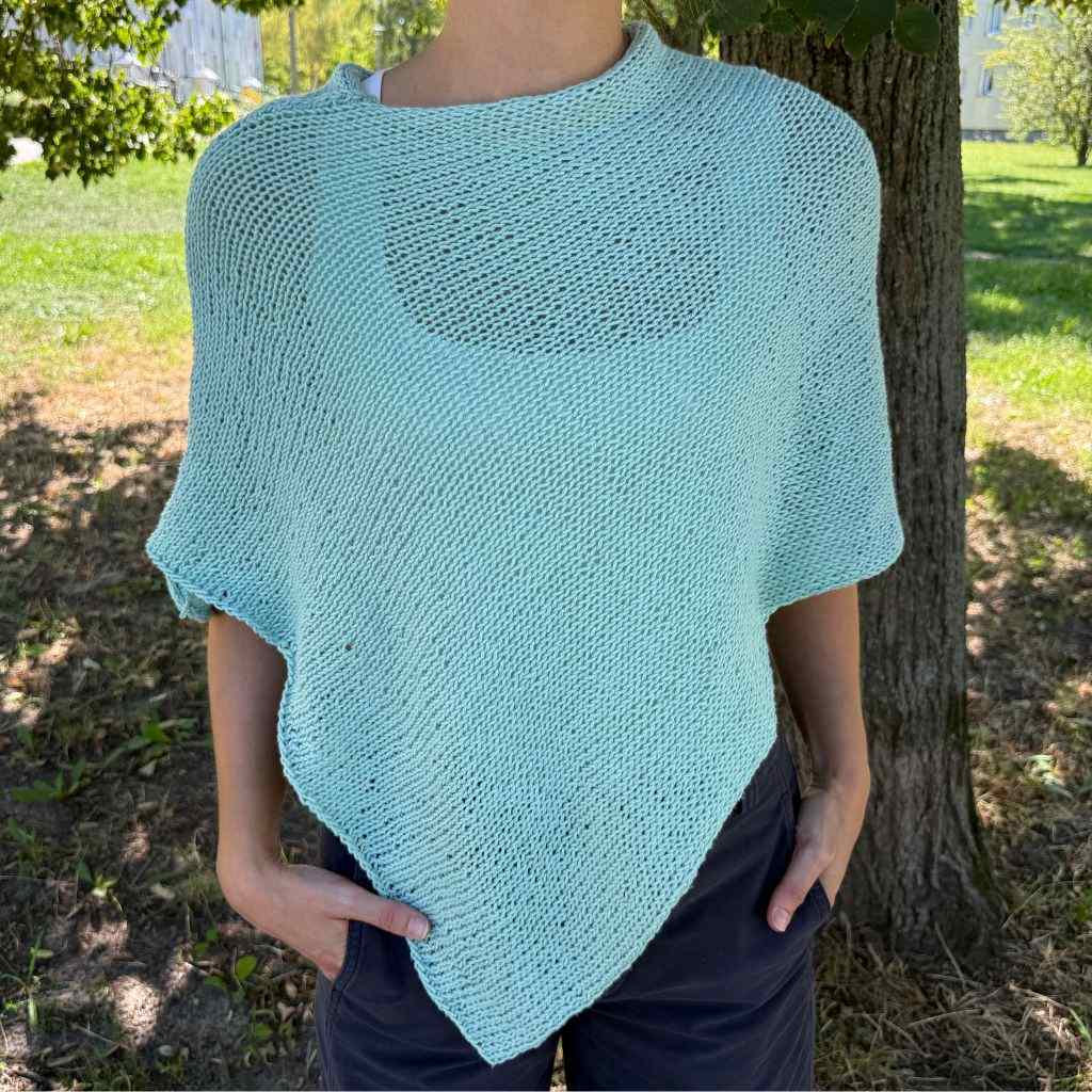 Person mit einem selbstgestrickten Poncho in Wasserblau.