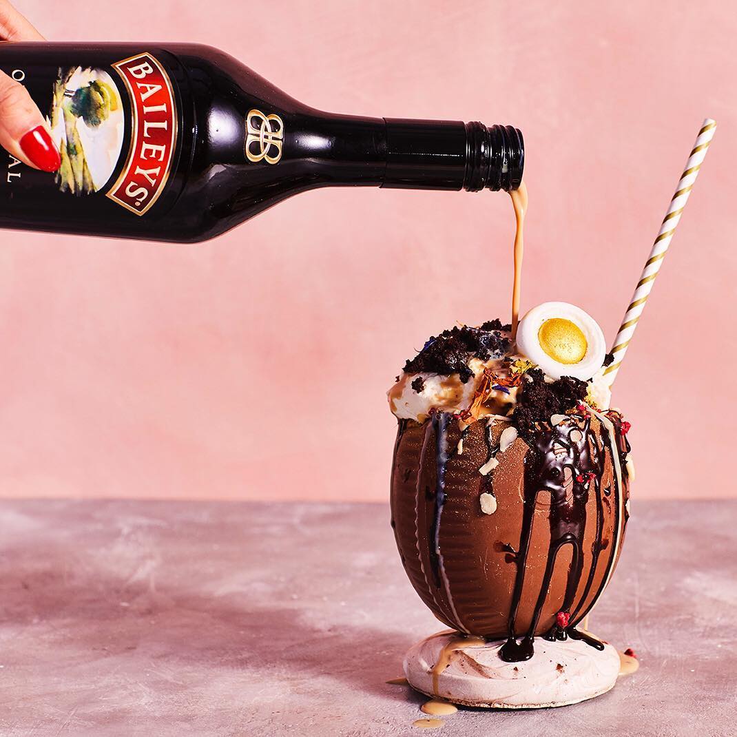 Easter egg cocktail with Baileys being poured into it.