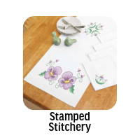 Stamped Stitchery. Image: Herrschners Pansy Parade Table Runner & Napkins Stamped Cross-Stitch.