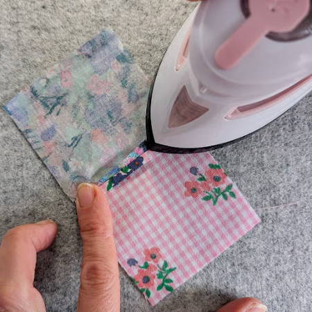 pressing a quilt block with a pink mini iron on a wool pressing mat