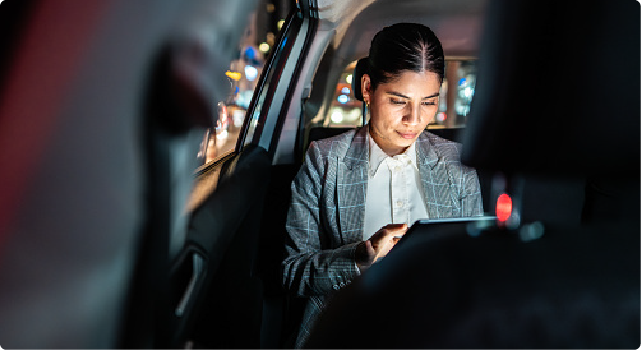 A woman in a car using a tablet at night.