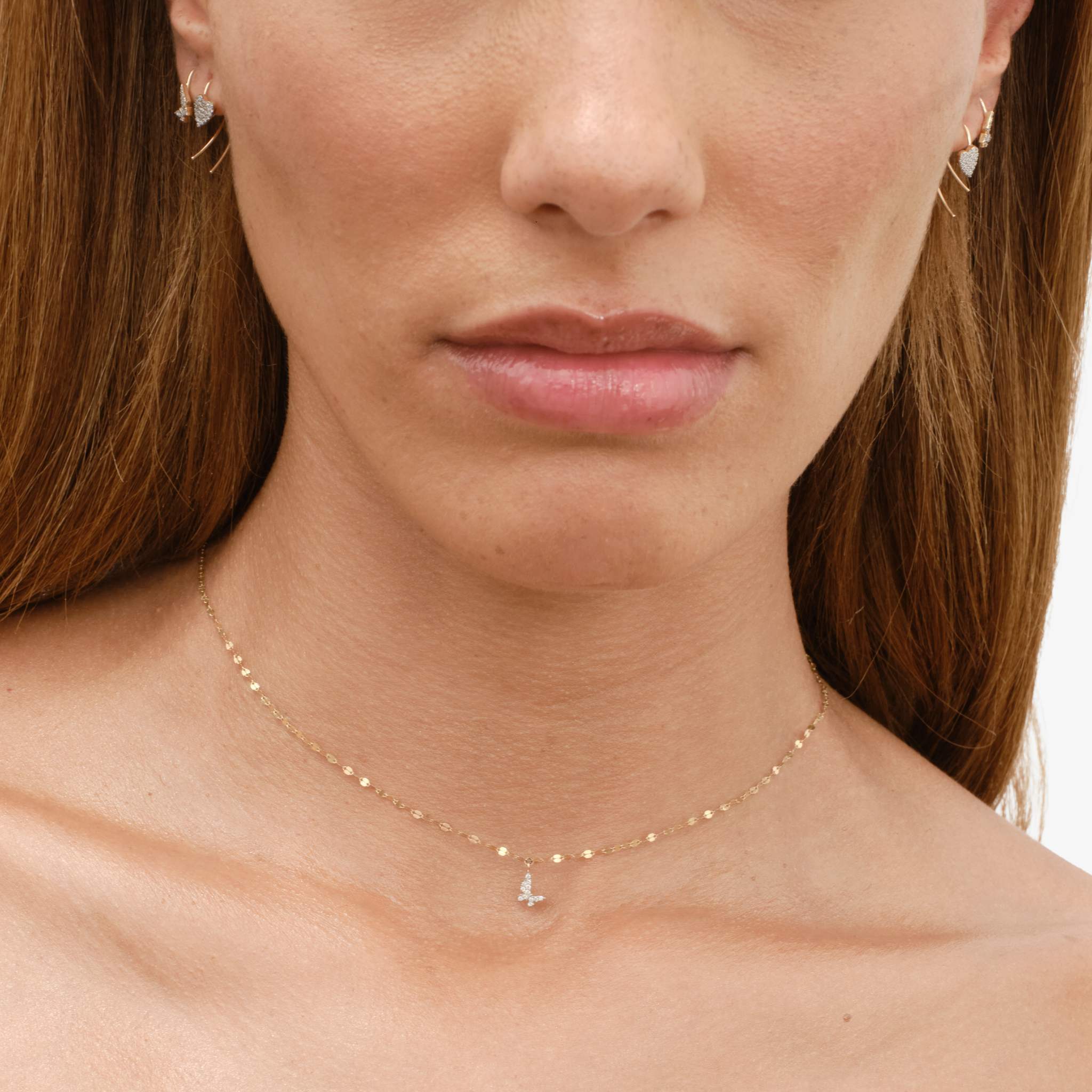 Close-up of a woman wearing jewelry, featuring earrings and a delicate necklace.