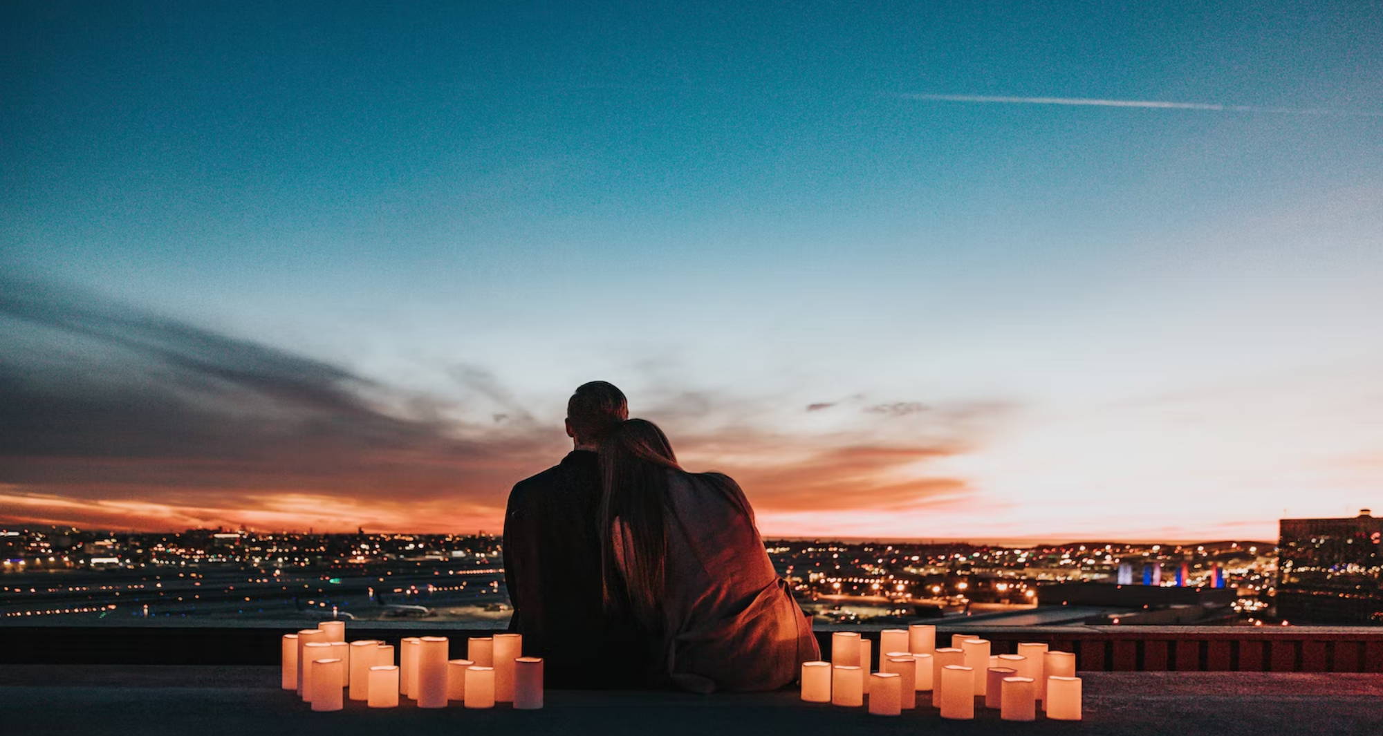 a couple sitting surrounded by lit candles at sunset