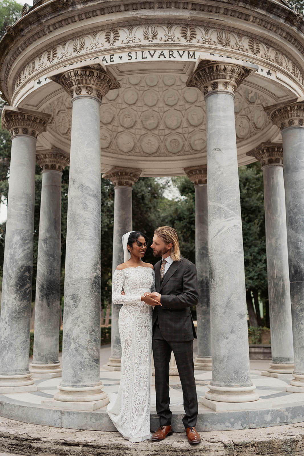 Bride and groom underneath pillar in Rome