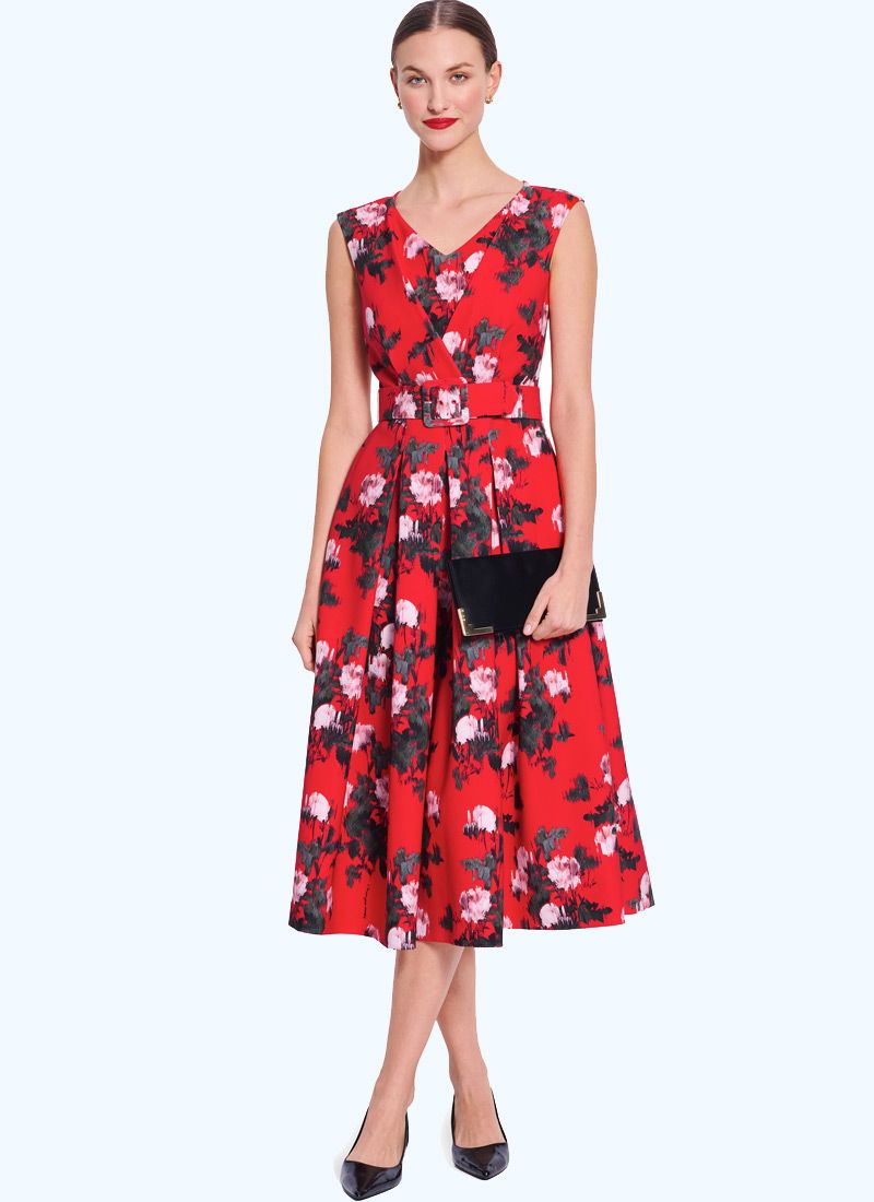 Woman in a floral red dress holding a black clutch.