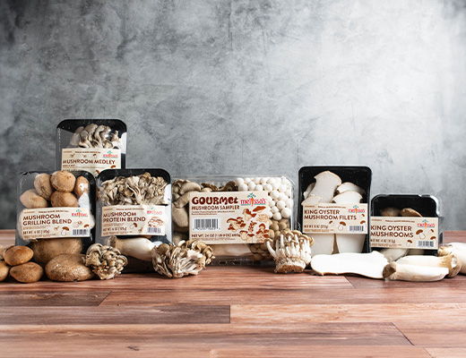 Various types of packaged mushrooms displayed on a wooden surface.