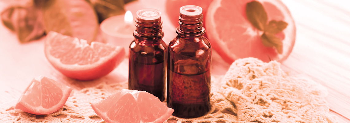 Two brown bottles surrounded by grapefruit slices and natural materials.