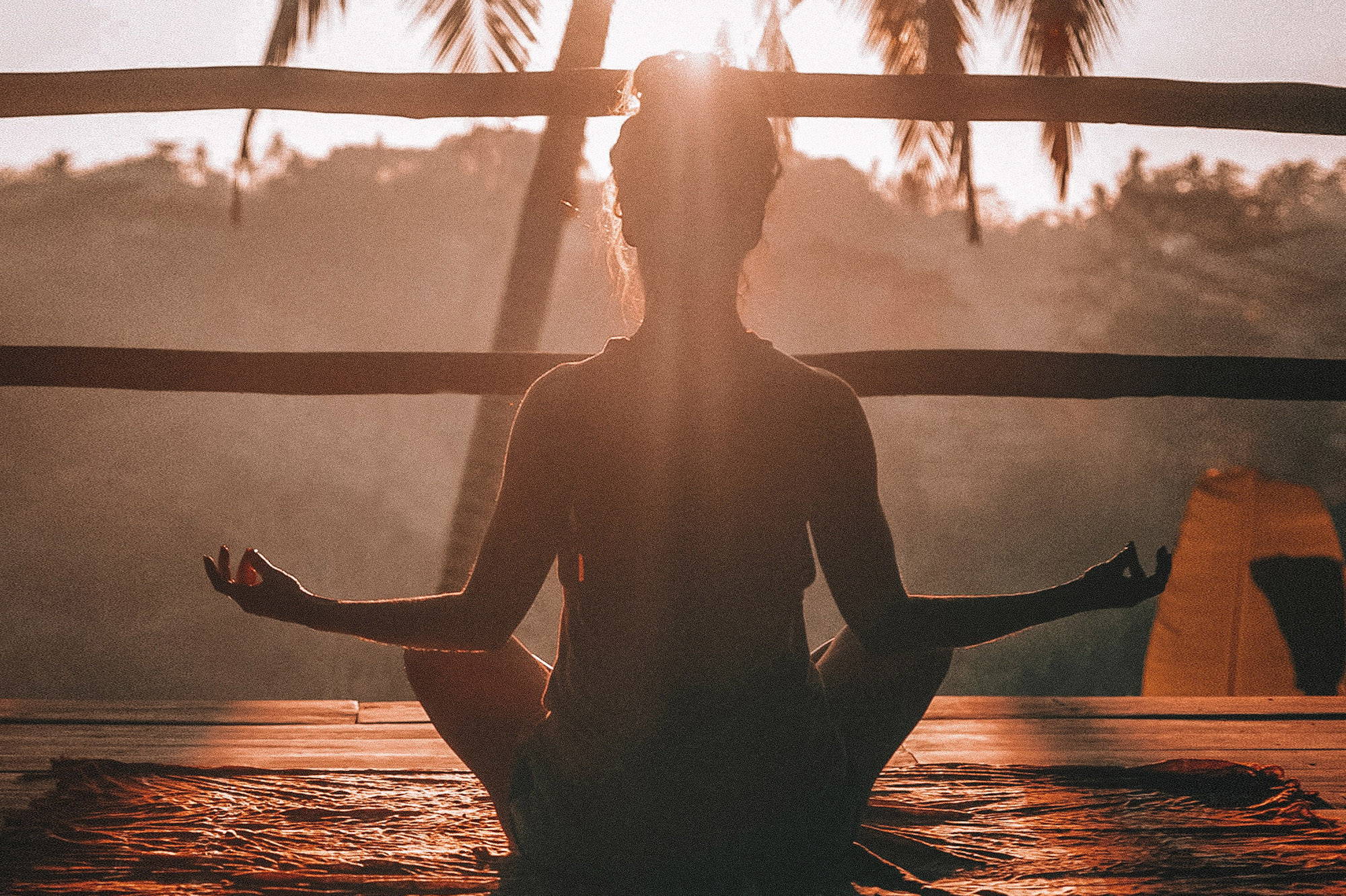 A woman meditating while sitting down in a tropical location