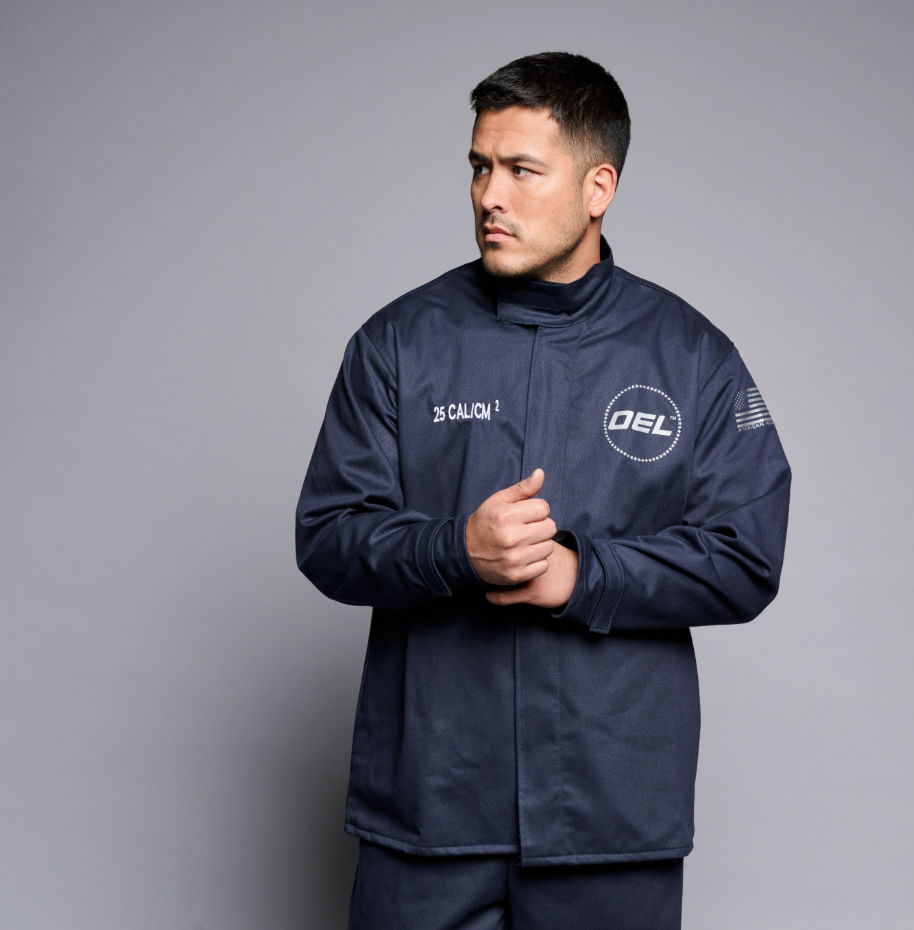 Man in a navy jacket standing against a gray background.