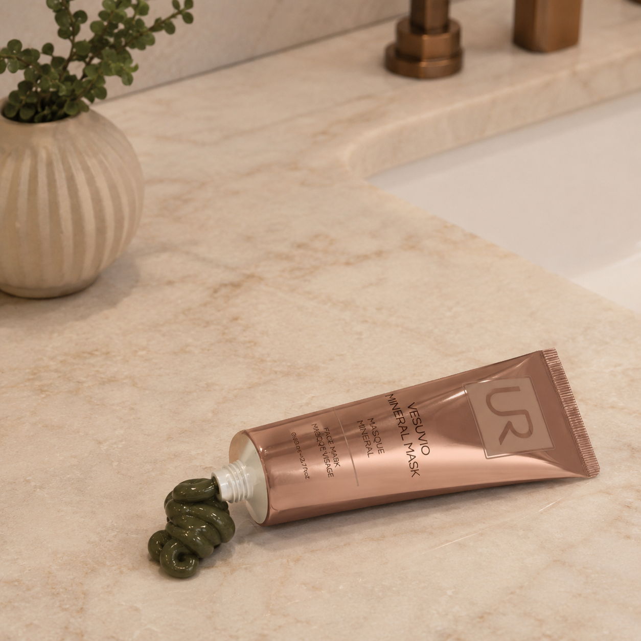 A tube of Vesuvio Mineral Mask skincare product on a marble countertop with a decorative vase.
