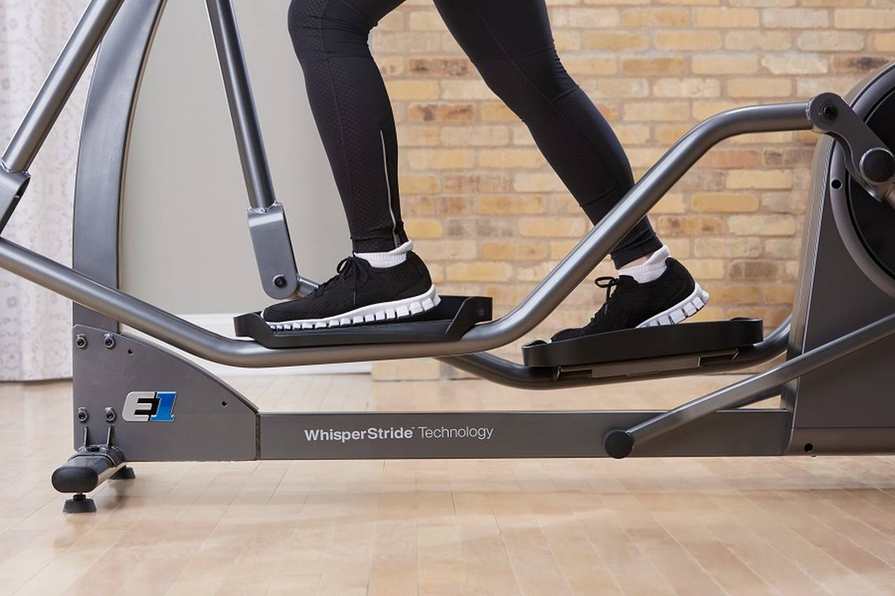 A person is riding an elliptical with whisper stride technology