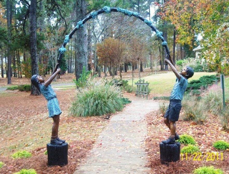 Bronze statue of a boy and girl holding an arbor in the park