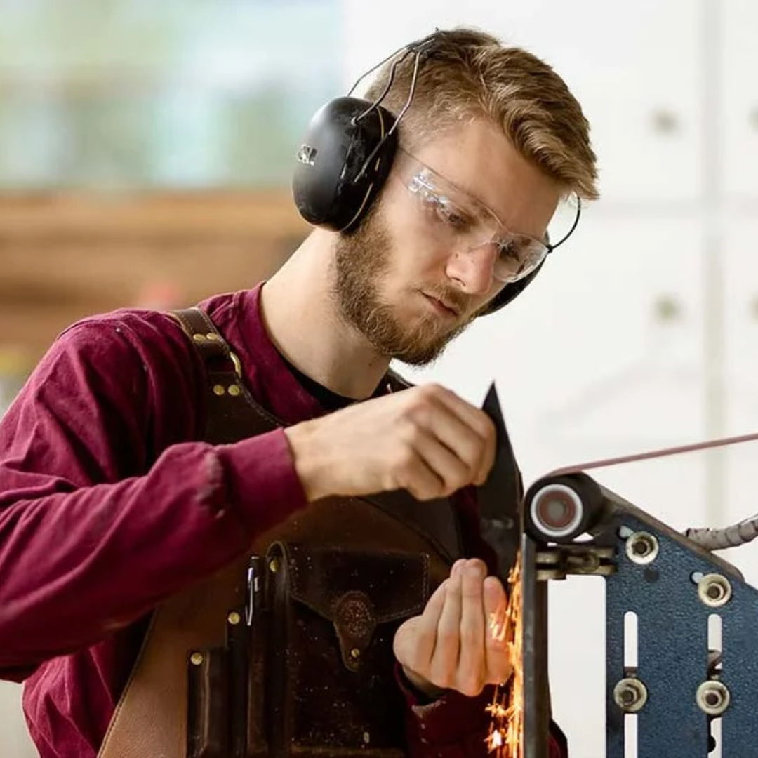 Person wearing safety gear working with machinery in a workshop.