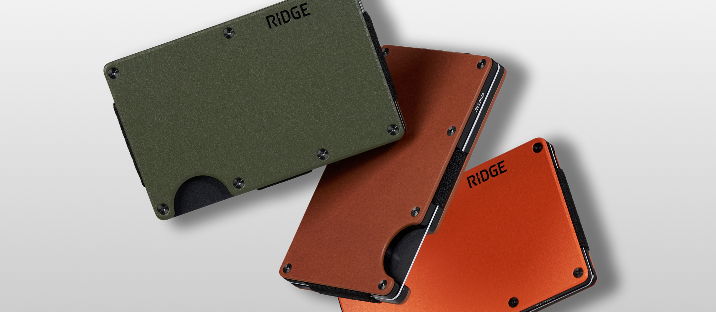 Three stylish wallets in green, orange, and red on a gray background.