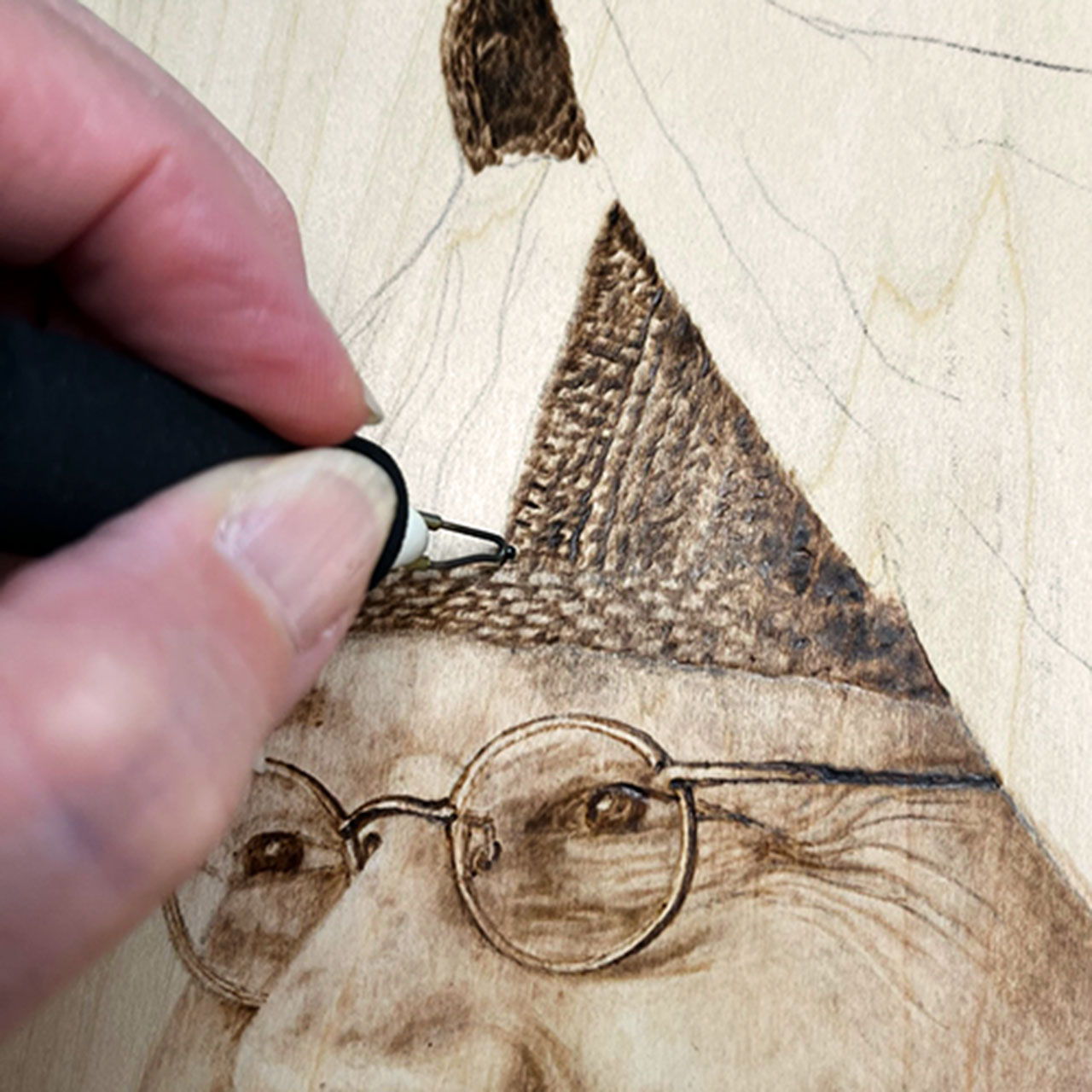A person using a tool to engrave an image on wood.
